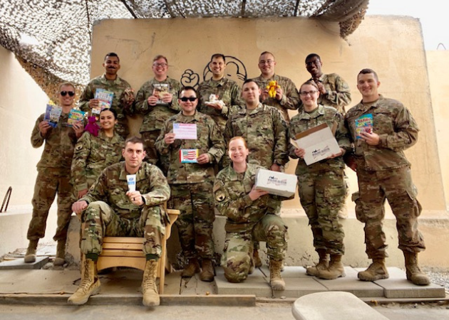 Deployed service members standing in a group holding Operation Gratitude Care Packages.