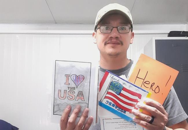 Deployed US service member holding up handwritten letters of gratitude.