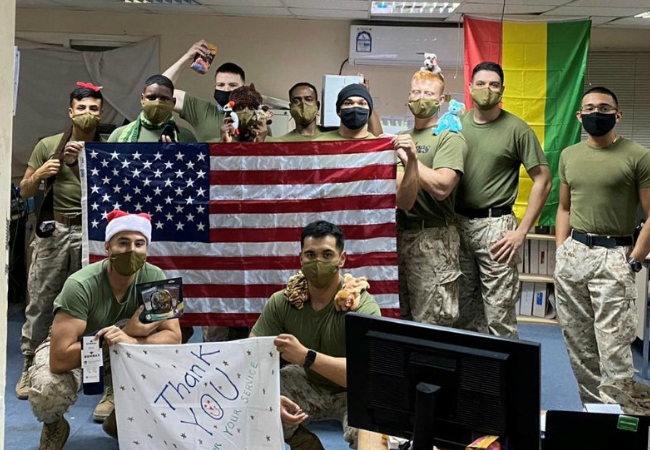 Deployed US service members holding a US flag.