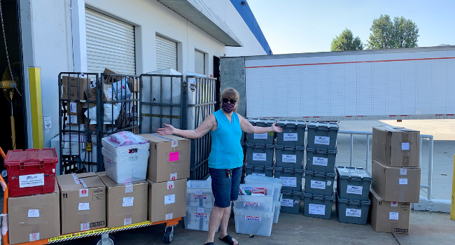 Volunteer displays boxes of donated items.