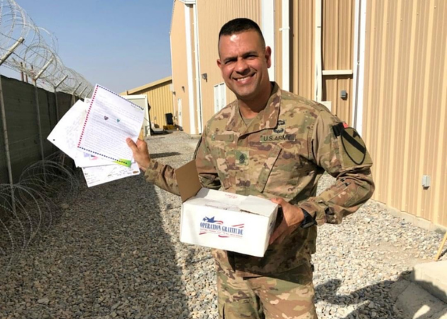 US Army soldier happily holding an Operation Gratitude Care Package and the handwritten letters he received. 