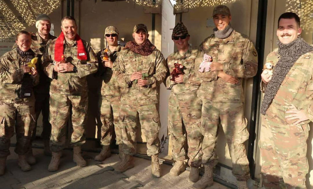 US Soldiers stand wear hats and scarves knit by Operation Gratitude volunteers.