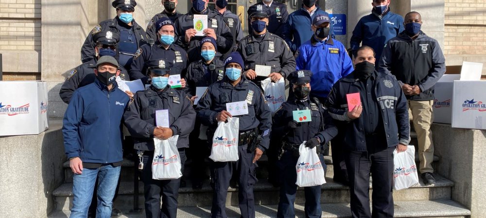 New York police officers standing on the steps smiling with Operation Gratitude care packages.