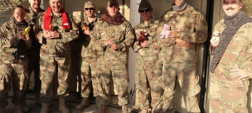 US Soldiers stand wear hats and scarves knit by Operation Gratitude volunteers.