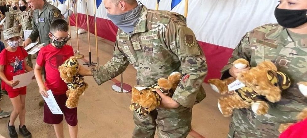 Service members hand out teddy bears to military children.